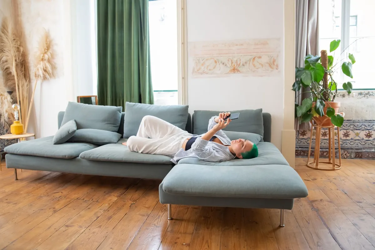 Person der ligger i sofaen med sin telefon