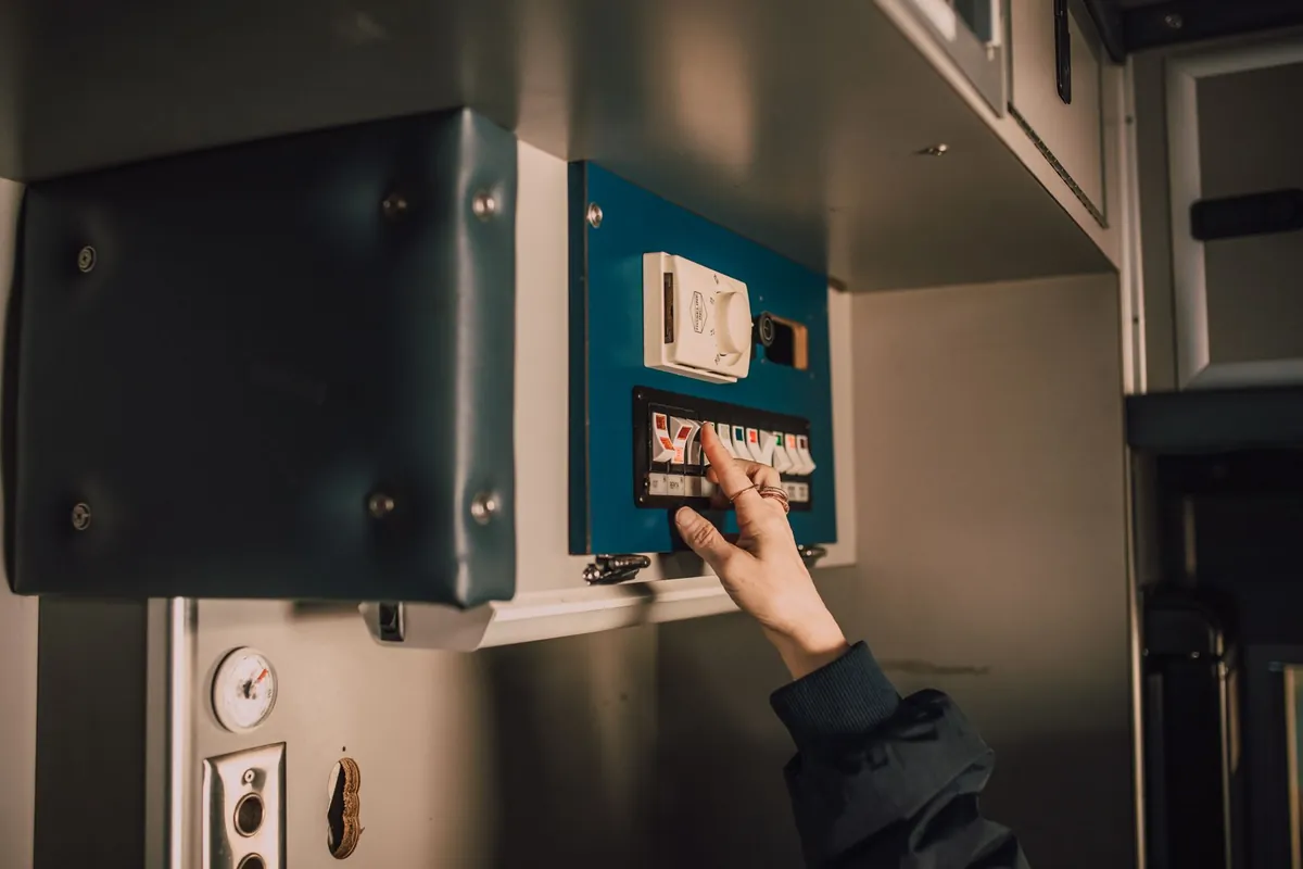 Hånd der slår kontakter til på et lille eltavle-panel